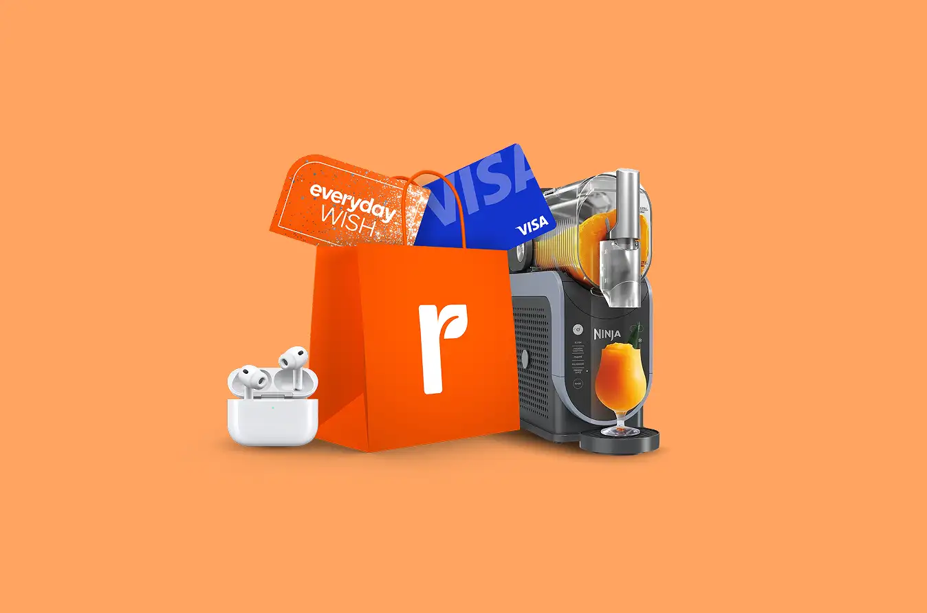 An orange shopping bag containing an "everyday WISH" gift card and a blue Visa card. Surrounded by a pair of white wireless earbuds and a Ninja Slushi machine pouring an orange frozen drink.