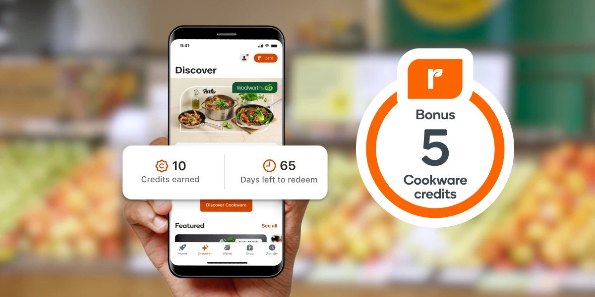 A hand holding a smartphone showing a Woolworths rewards app interface for a cookware promotion